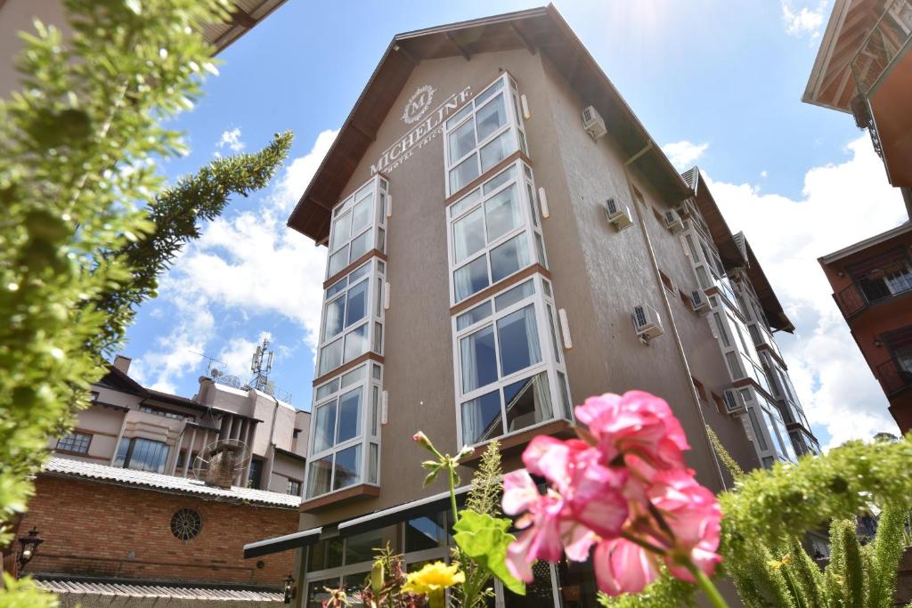 um edifício com uma flor rosa à frente dele em Micheline Hotel Tricot - ao lado da Rua Coberta em Gramado
