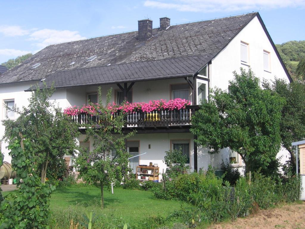 ein weißes Haus mit rosa Blumen auf dem Balkon in der Unterkunft Weinfelderhof in Kröv