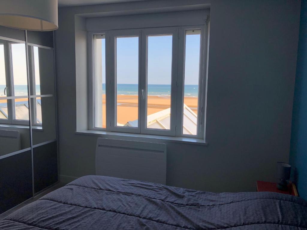 a bedroom with a bed and a view of the ocean at La Plage d'Or in Vierville-sur-Mer