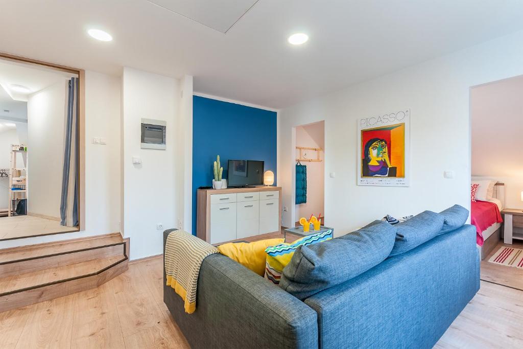 un salon avec un canapé bleu et une télévision dans l'établissement TOP Apartman, à Zagreb