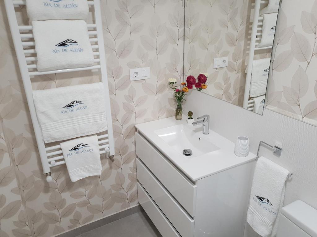a white bathroom with a sink and a mirror at Apartamentos Ria de Aldan in Aldán