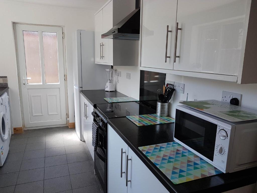a kitchen with white cabinets and a black counter top at Central Location Preston 2 in Preston