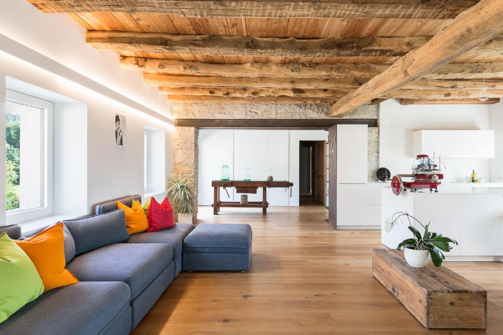 a living room with a blue couch and wooden ceilings at Relais Poggio Pagnan in Farra