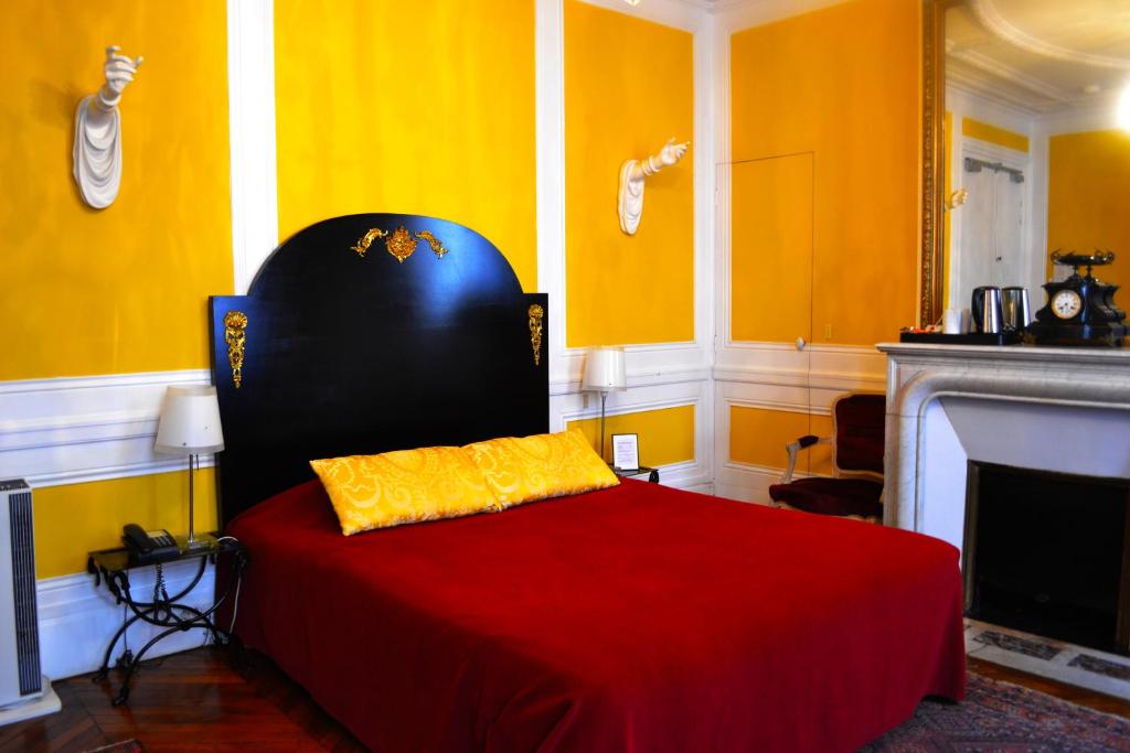 a bedroom with a bed with a red blanket and a fireplace at Hotel Windsor Home in Paris