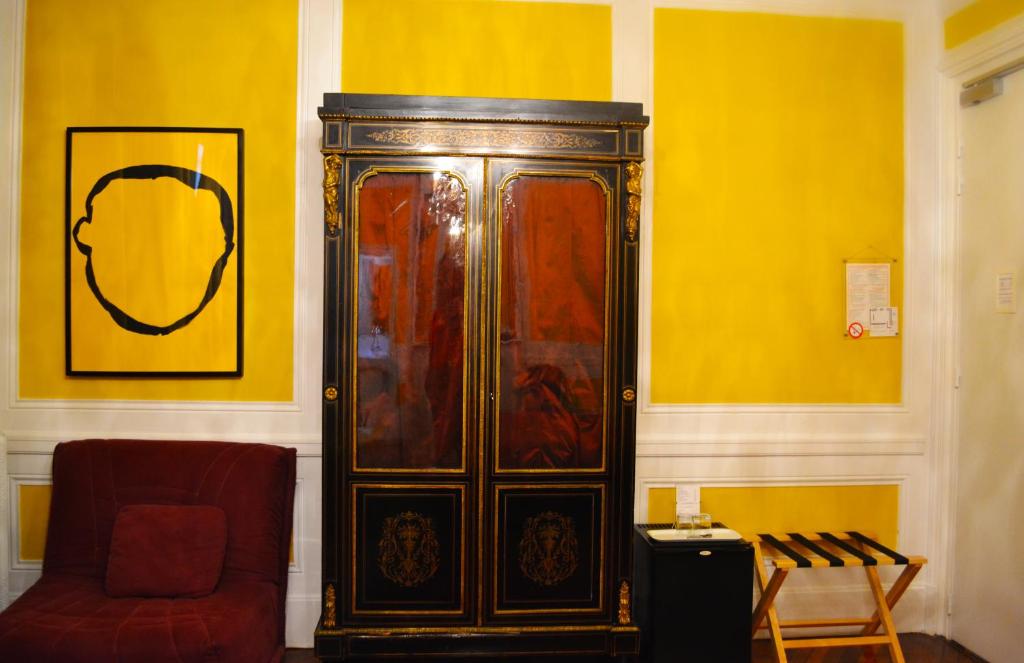 a large wooden cabinet in a room with a red chair at Hotel Windsor Home in Paris