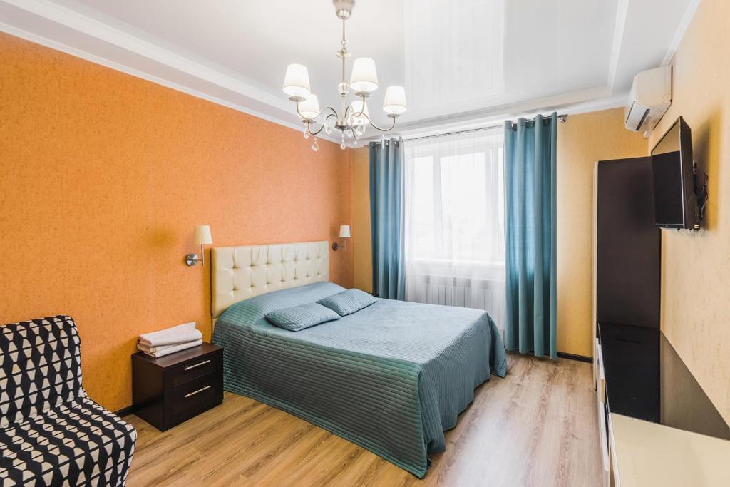 ブズルクにあるМосковская 79のベッドルーム(ベッド1台、テレビ、椅子付)