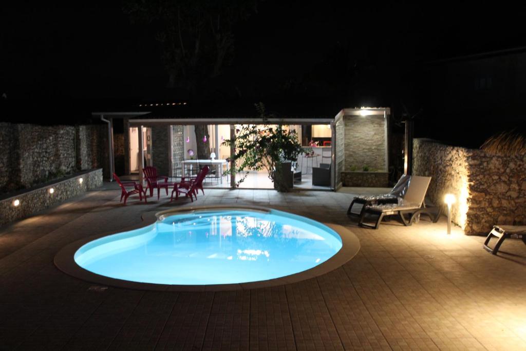 una piscina por la noche con sillas y una mesa en villa du vieux moulin de gissac, en Sainte-Anne