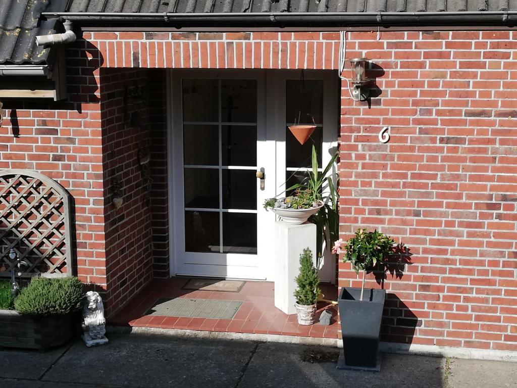 a brick house with a white door with plants on it at Süderdeich in Koldenbüttel