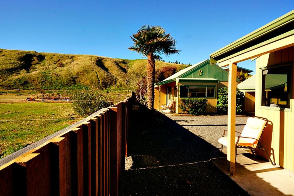 a house with a fence and a palm tree at Bay Cottages in Kaikoura