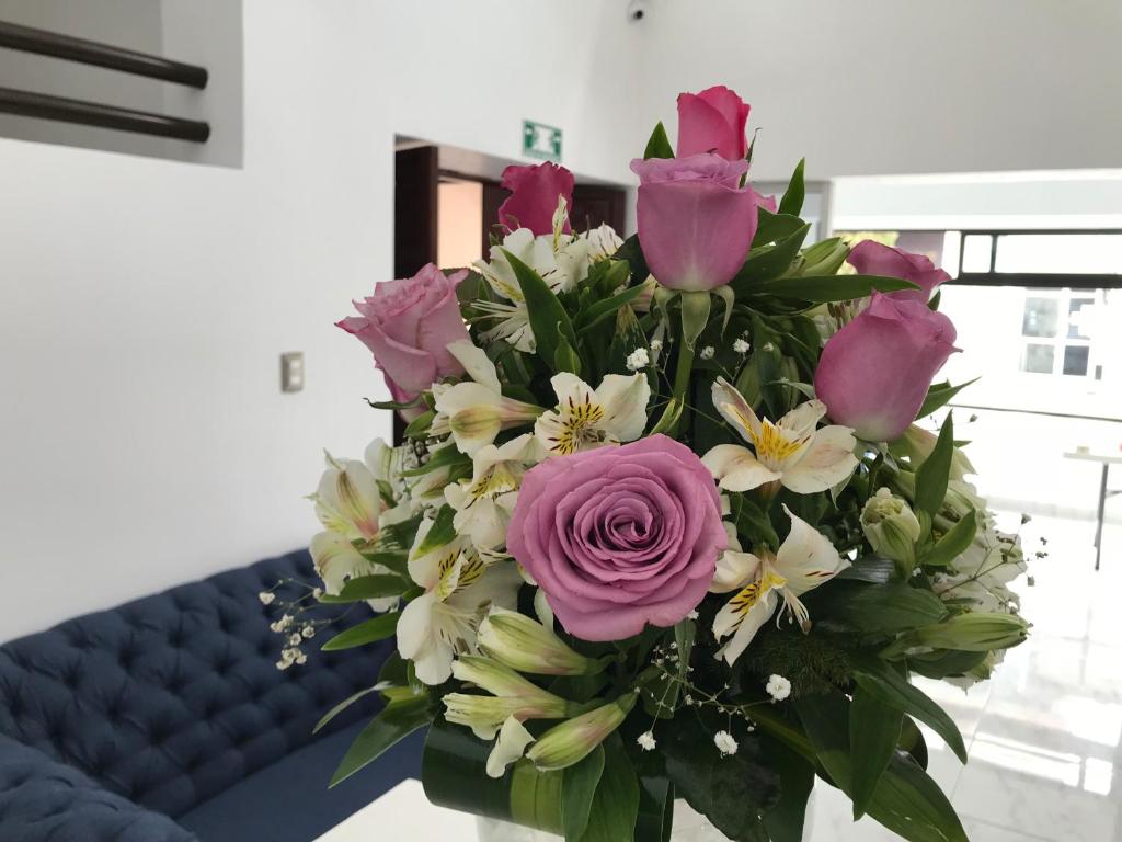 un bouquet de fleurs roses et blanches sur une table dans l'établissement Hotel Plaza Amalia, à Tuxtla Gutiérrez