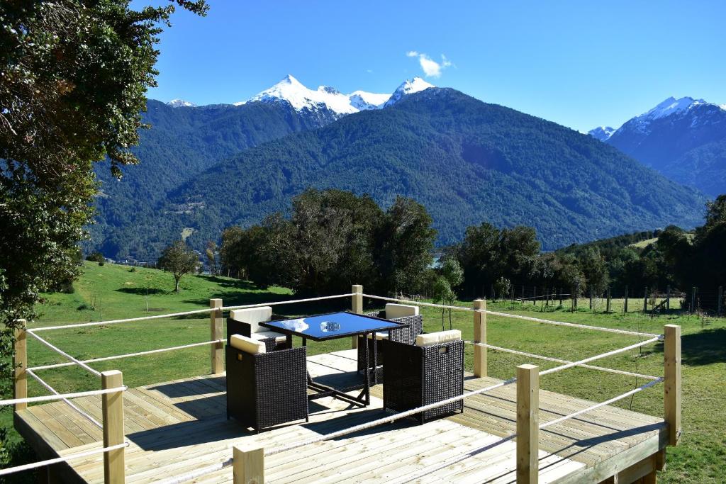 a picnic table on a deck with mountains in the background at Las Bandurrias Eco Hostal in Cochamó