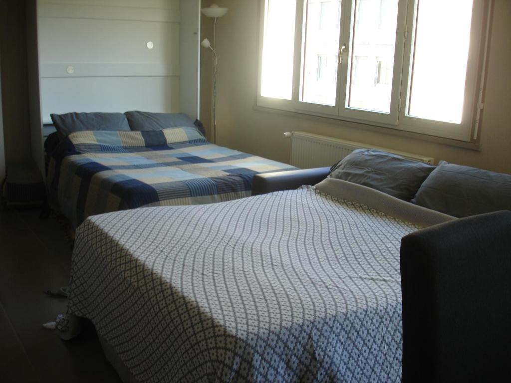 a room with two beds and a couch and a window at Studio Centre Ville Office De Tourisme in Bayonne