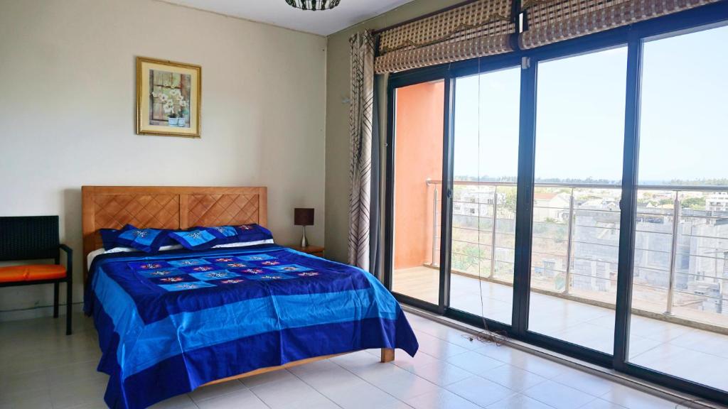 a bedroom with a bed and a large window at Palmyre Residence 7 & 8 LICENSED BY TOURISM AUTHORITY 10071 in Flic-en-Flac