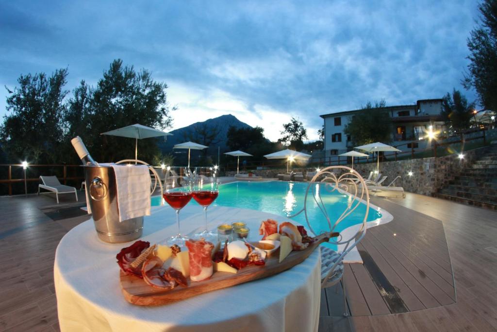 a tray of food and wine on a table next to a pool at Tenuta Terre di Bosco Oasi di Relax nel Cilento in San Giovanni a Piro