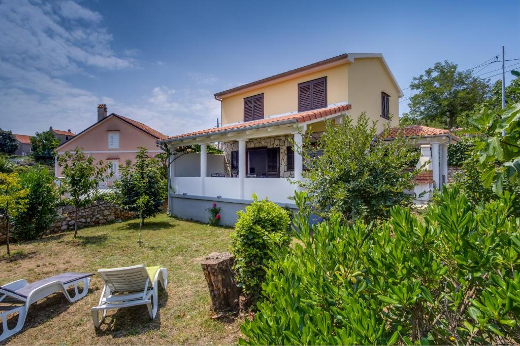 una casa con sillas de jardín delante de ella en Vila Mirta, en Nerezine