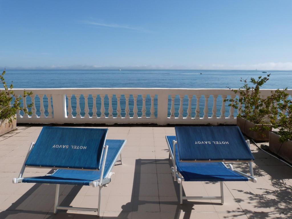 - deux chaises de plage bleues assises sur un balcon donnant sur l'océan dans l'établissement Hotel Savoy, à Varazze