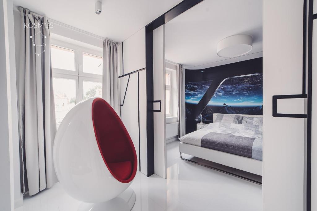 sypialnia z czerwonym krzesłem przed łóżkiem w obiekcie Kosmos 9 - Apartament Orbita w Toruniu