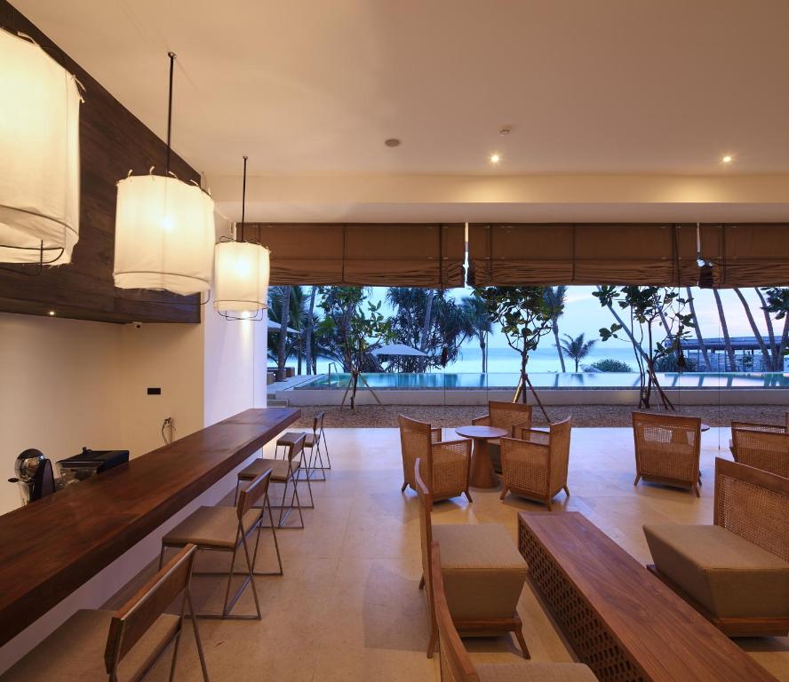 a restaurant with a long bar with chairs and tables at Riff Hikkaduwa in Hikkaduwa