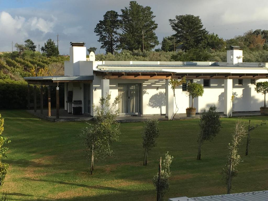 a white house with a green lawn in front of it at Klein Welmoed Luxury Guest House in Stellenbosch