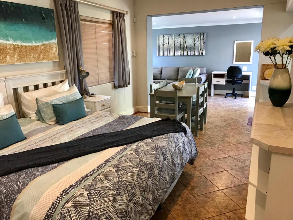 a bedroom with a bed and a desk and a room at Cosy Private Cottage in Port Elizabeth