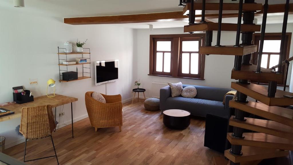 a living room with a blue couch and a staircase at Haus zum wilden Manne in Erfurt
