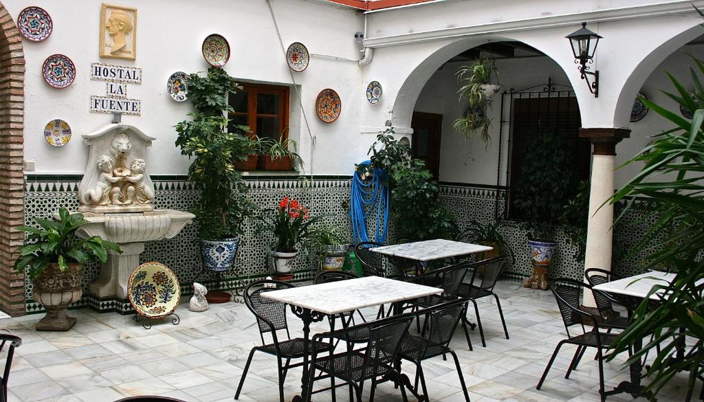 eine Terrasse mit Tischen, Stühlen und einem Brunnen in der Unterkunft Hostal la Fuente in Córdoba