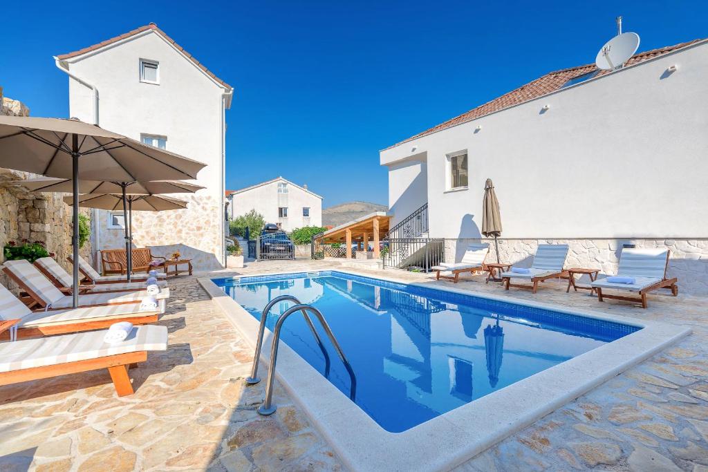 einen Pool mit Stühlen und einem Sonnenschirm neben einem Haus in der Unterkunft Villa Trau d`oro in Trogir