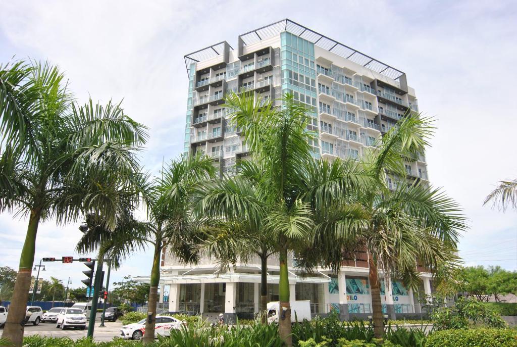 ein hohes Gebäude mit Palmen davor in der Unterkunft One Madison Place Tower 1 in Iloilo City