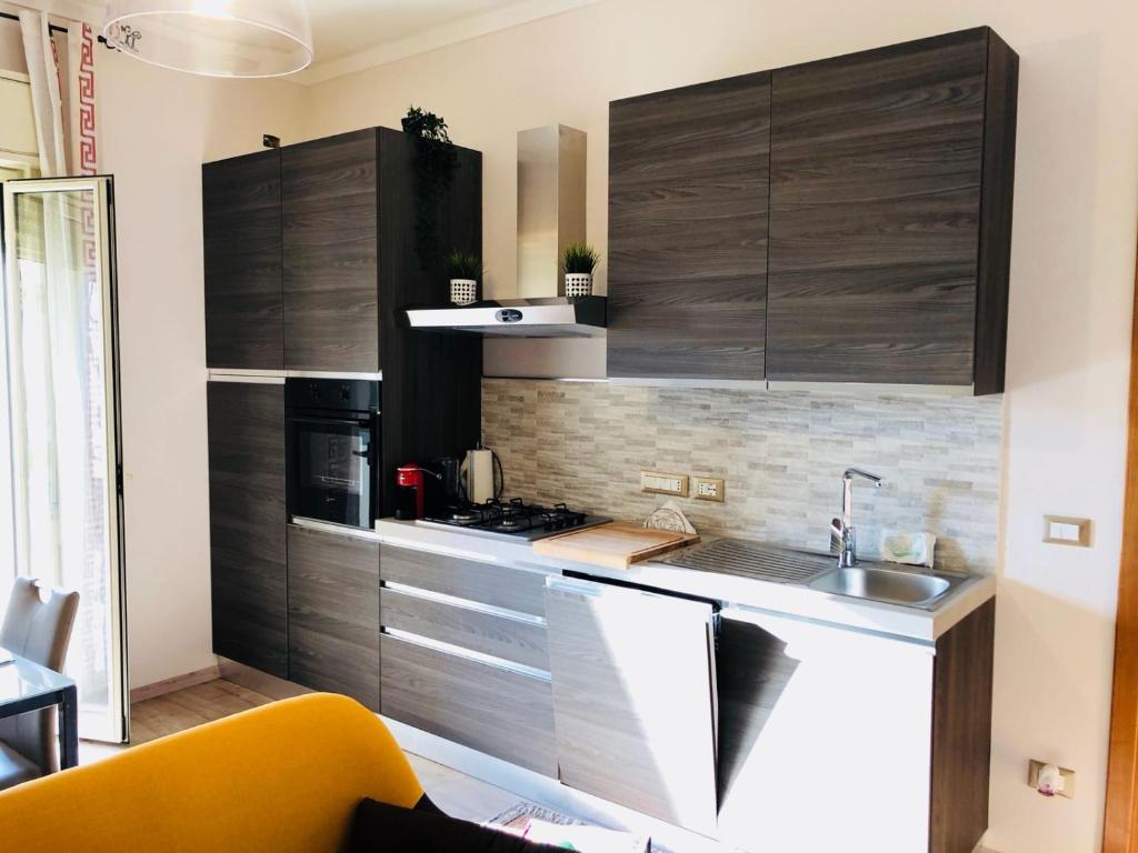 una cocina con armarios de madera y fregadero en SL Apartament, en San Gregorio di Catania