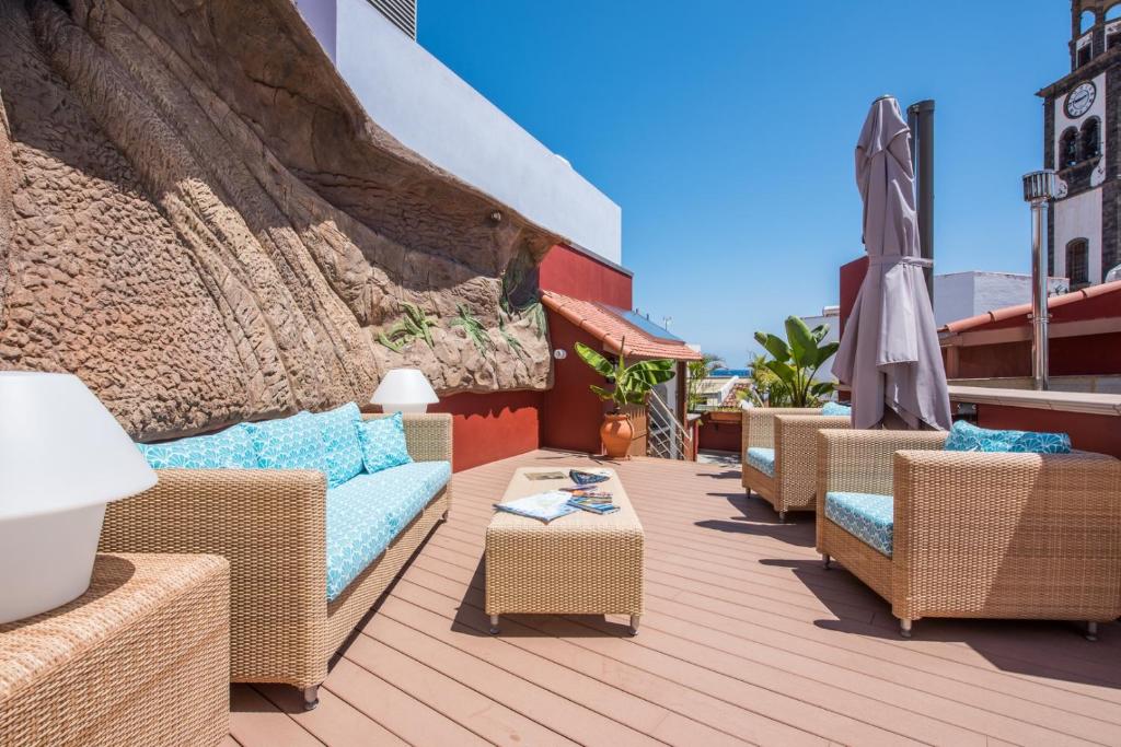 a patio with wicker chairs and tables and an umbrella at Casa Emblemática Topacio in Santa Cruz de Tenerife