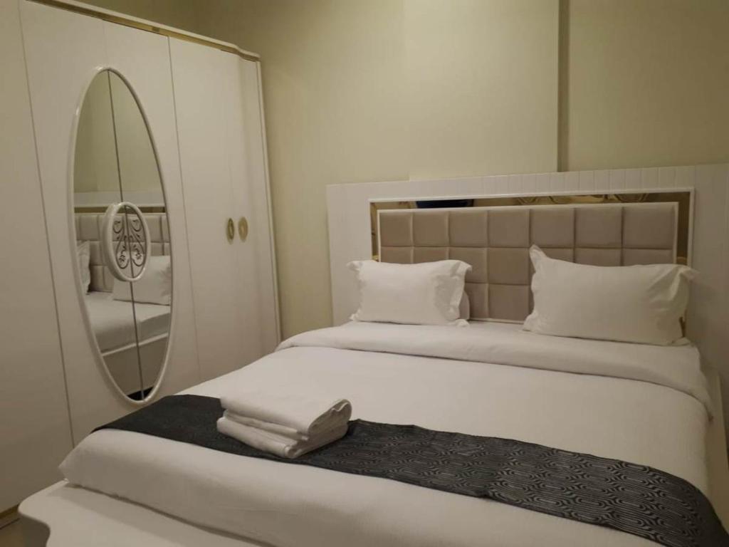 Reef Hotel Aparts (Tabasum Group) في عجمان: غرفة نوم مع سرير أبيض كبير مع مرآة