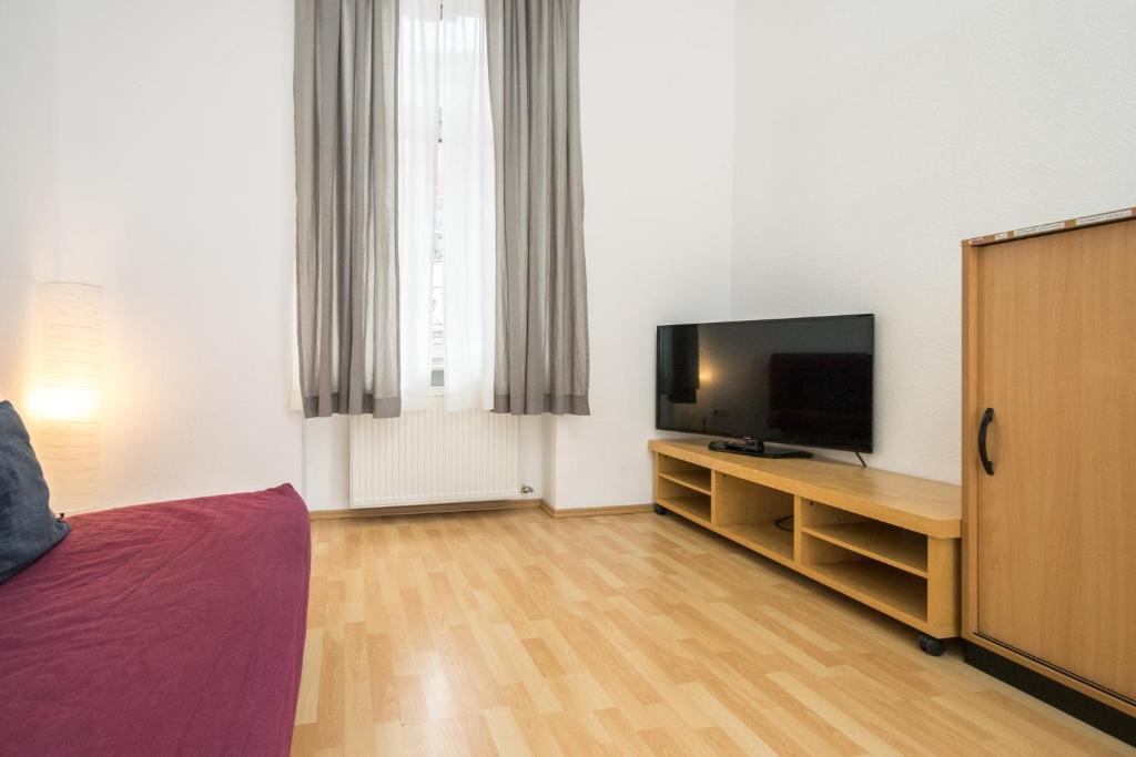 uma sala de estar com uma televisão e uma cama em Tulpen Residenz em Offenbach