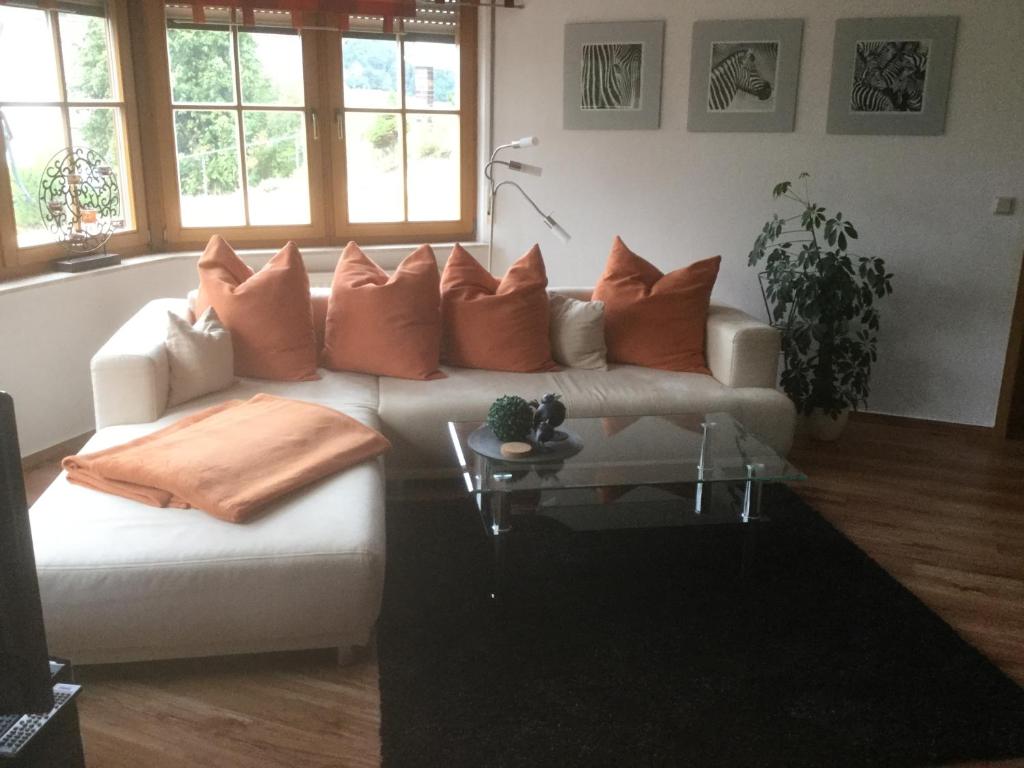 a living room with a white couch with orange pillows at FW Sonnenschein in Wechterswinkel