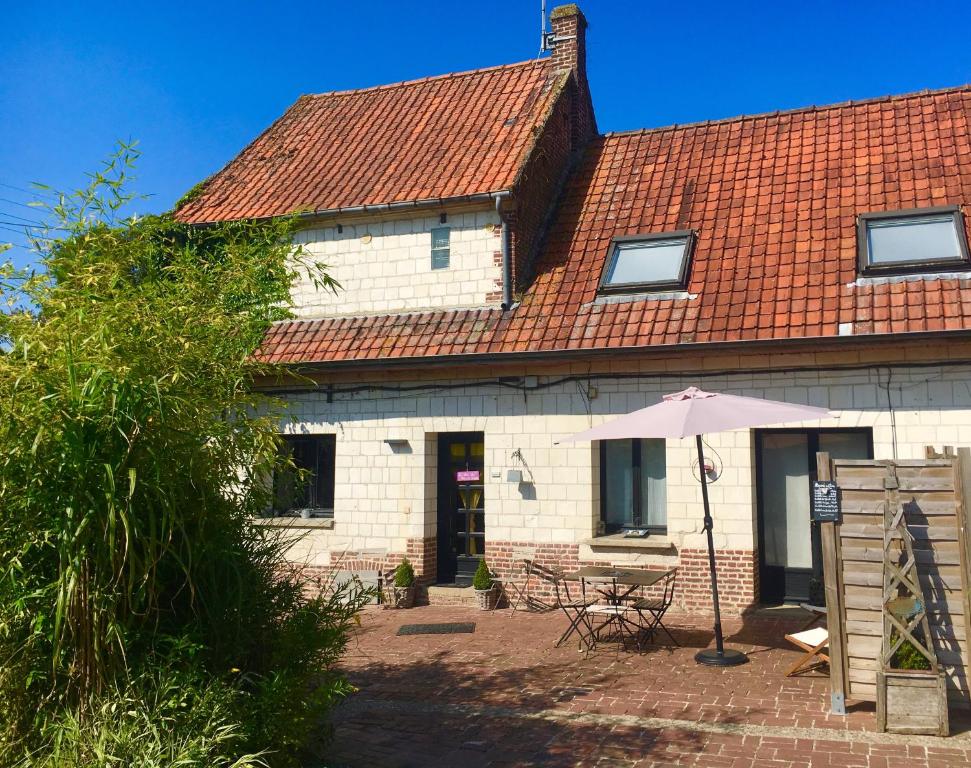 une maison avec une table et un parasol devant elle dans l'établissement Le Clos du Carpe Diem, à Cambligneul