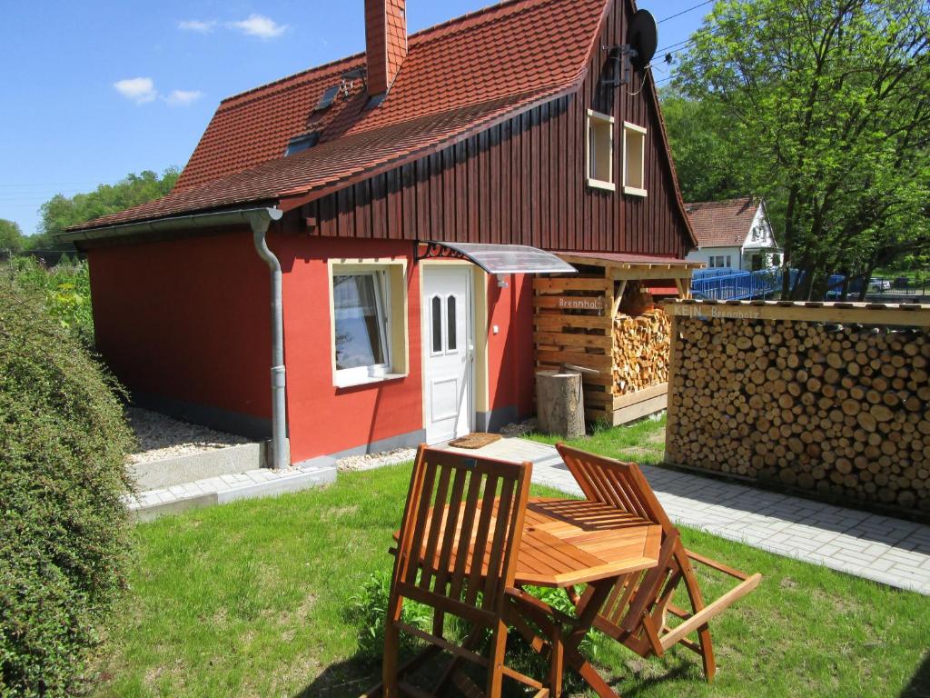 a house with a table and two chairs in front of it at Mandauhaus mit Sauna in Hainewalde