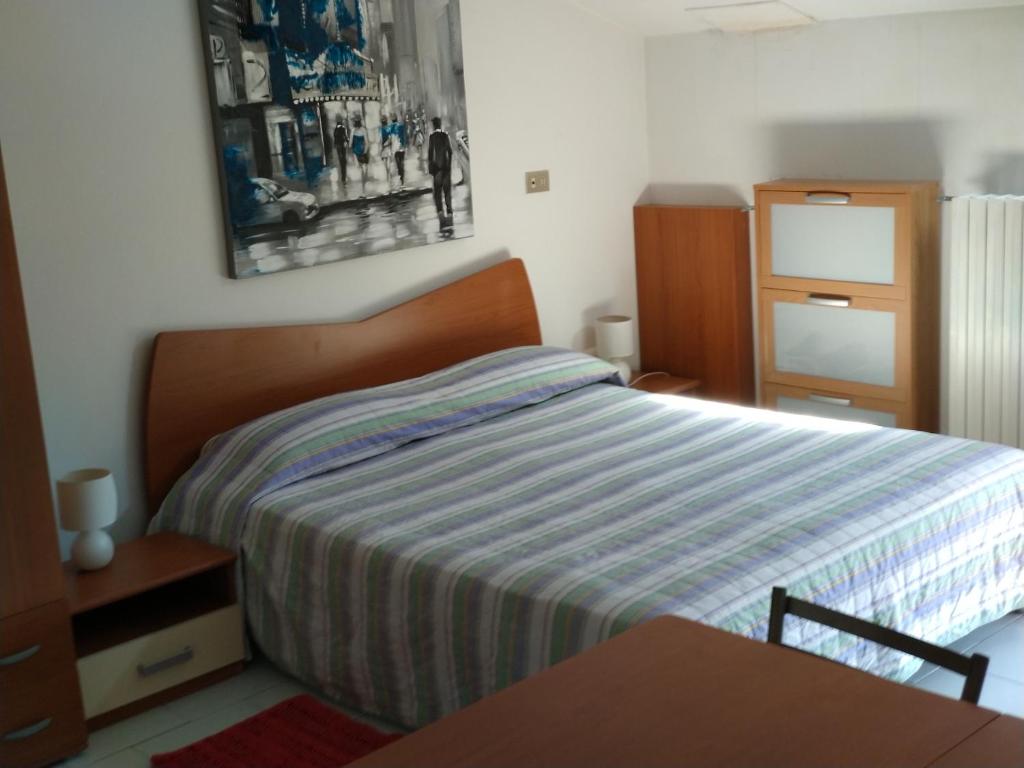 - une chambre avec un lit avec une couverture rayée et une table dans l'établissement Monolocale Stella, à San Benedetto del Tronto