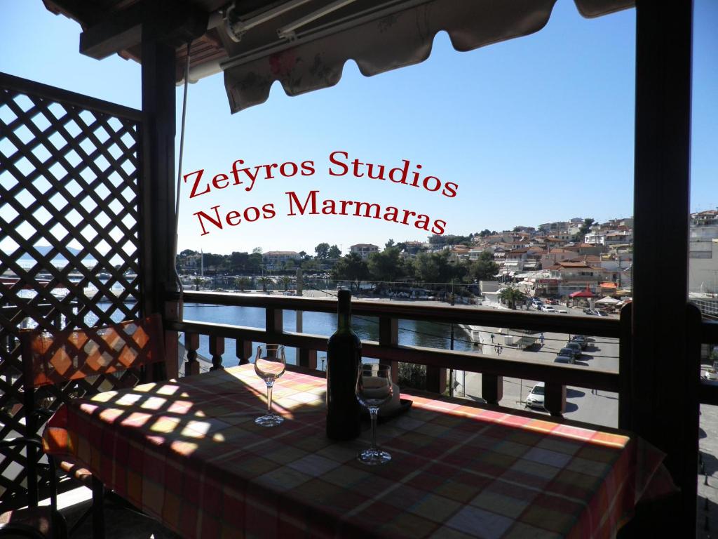 una mesa con una botella de vino en el balcón en Zefyros Studios, en Neos Marmaras