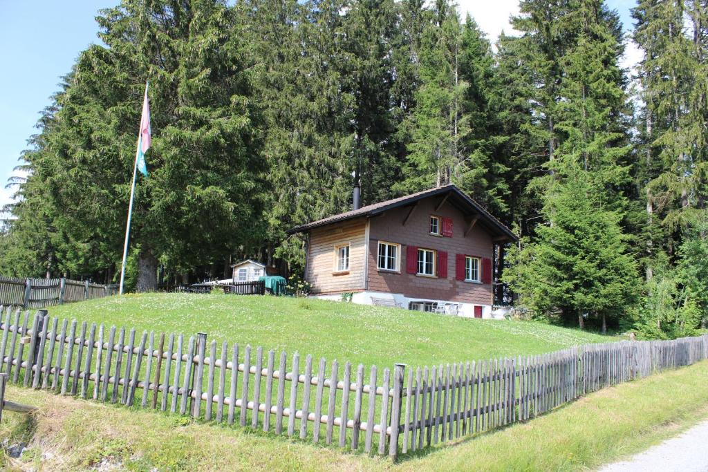 Ein Haus auf einem Hügel mit einem Zaun und einer Flagge in der Unterkunft Chalet Nueschwendi in Ebnat