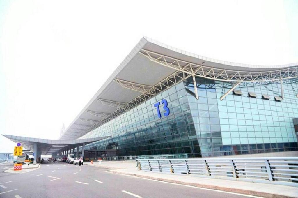 a large glass building with a parking lot in front of it at One Meter Sunshine Xi'an Xianyang International Airport Hotel in Xianyang