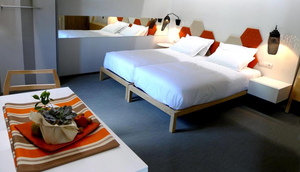 a hotel room with two beds and a table at Blanco Apartamentos Turísticos in Santiago de Compostela