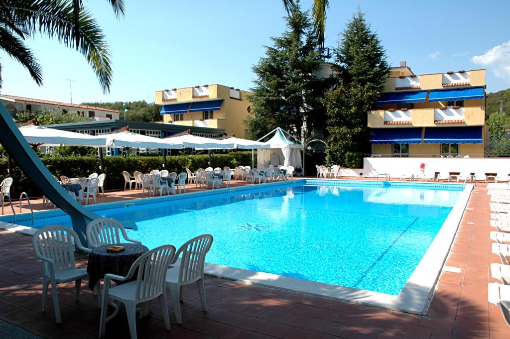 a swimming pool with chairs and a table and a building at Hotel Seven Residence in Palinuro