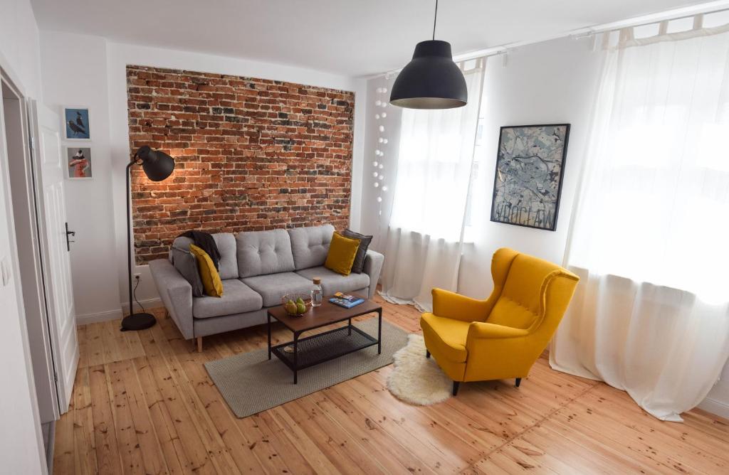 - un salon avec un canapé et un mur en briques dans l'établissement CityBrejk Hubska Wrocław, à Wrocław