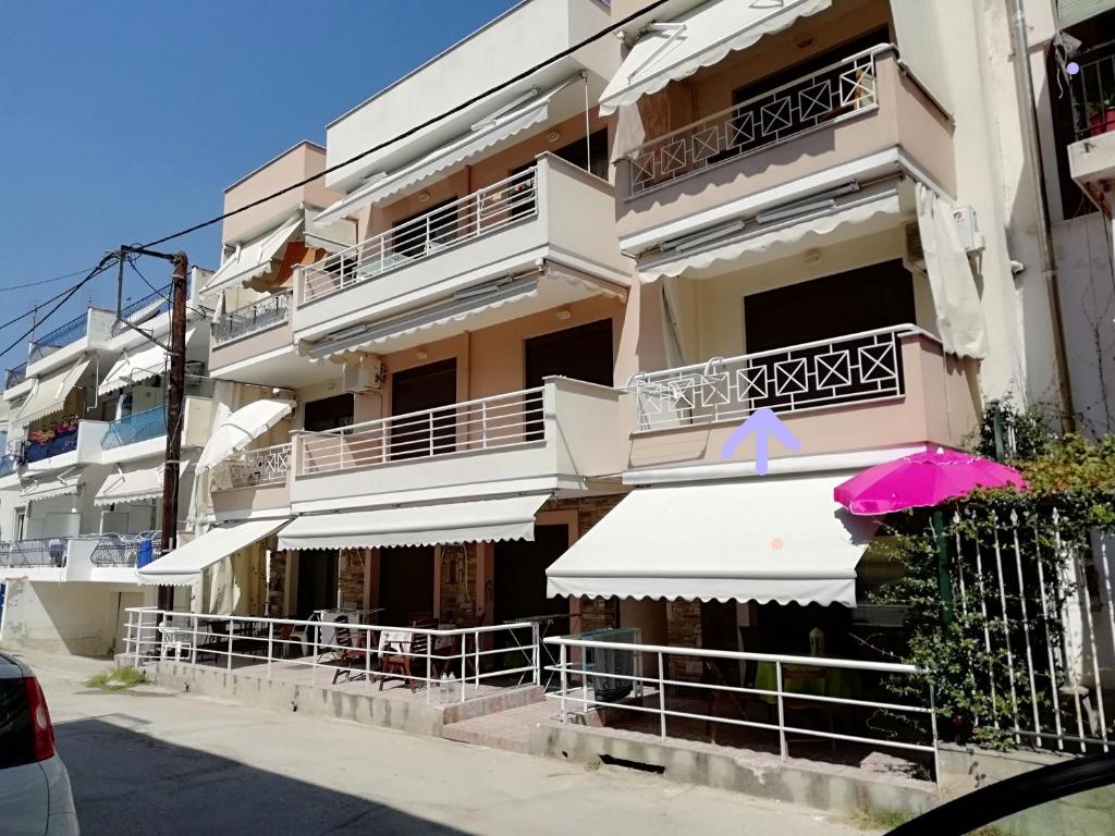 ネア・ペラモスにあるCHRISTINA APARTMENT ΝΕΑ ΠΕΡΑΜΟΣのピンクの傘が前に置かれた建物