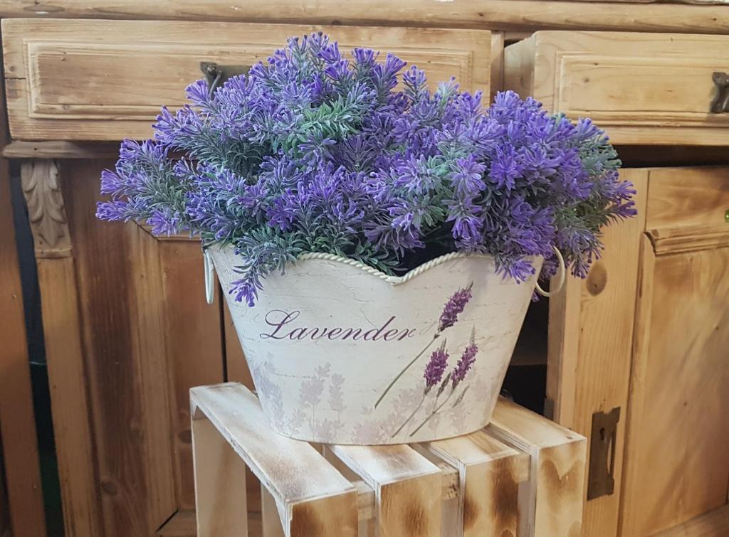 a bucket of purple flowers sitting on a stool at Levendula Apartman in Szekszárd