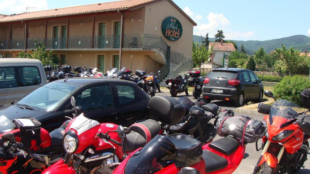 een stel motorfietsen geparkeerd voor een gebouw bij Abel Hôtel in Langeac