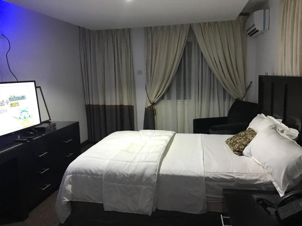 a hotel room with a bed and a flat screen tv at Hotel Cabenda in Freetown