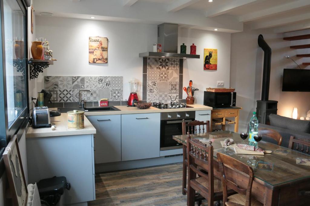 a kitchen with white cabinets and a dining table at Le Pailhé de Marius in La Salvetat