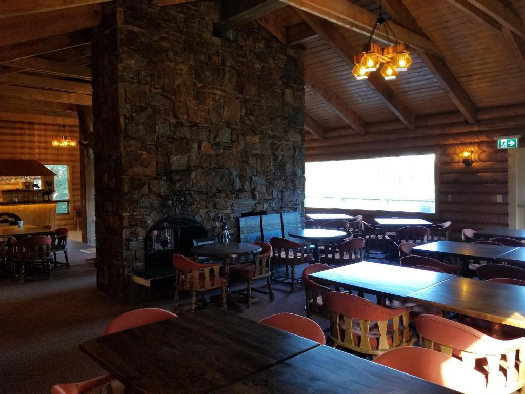 a restaurant with tables and chairs and a stone wall at Schott's Lake Conference & Resort in Sundre