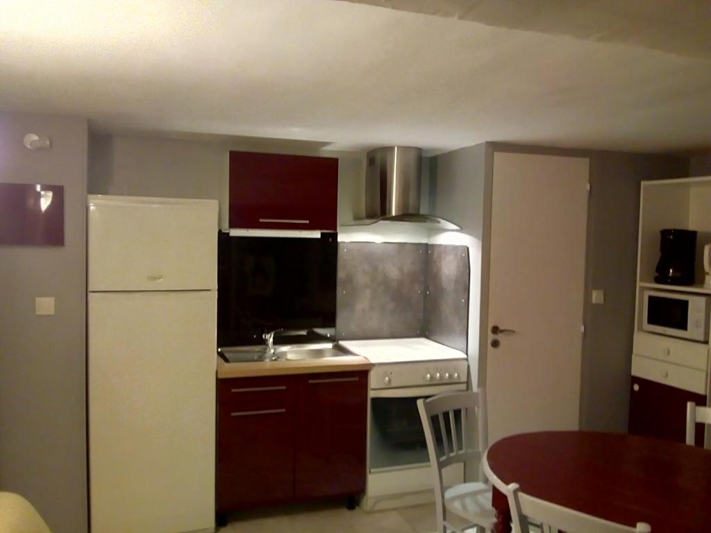 a small kitchen with a white refrigerator and a table at 7 Rue du Docteur Paul Jouve in Digne-les-Bains