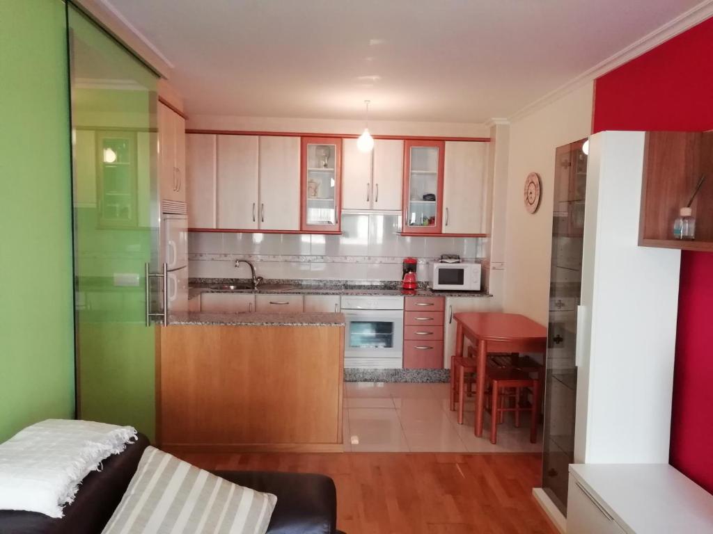 una cocina con armarios blancos y una mesa roja en Calle Maceiras, 1 - 1B, en Combarro